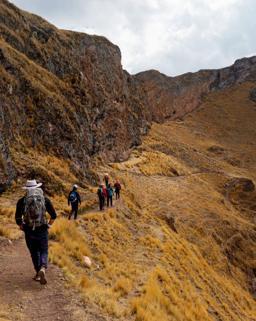 Hikers on a high-altitude trail through golden puna grassland in the Peruvian Andes